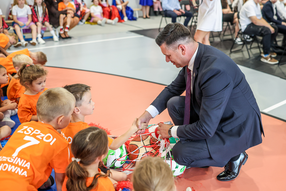 marszałek Łukasz Smółka wita się z dziecmi w hali sportowej