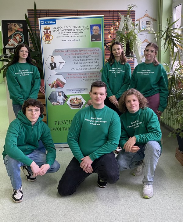 Na fotografii sześciu uczniów Zespołu Szkół Przemysłu Spożywczego w Krakowie stoi przed plakatem informacyjnym w szkole.