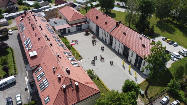 Na fotografii z lotu ptaka widać dziedziniec szkolny otoczony budynkami szkolnymi z trzech stron. Wokół kompleksu szkolnego znajdują się tereny zielone i 2 parkingi.