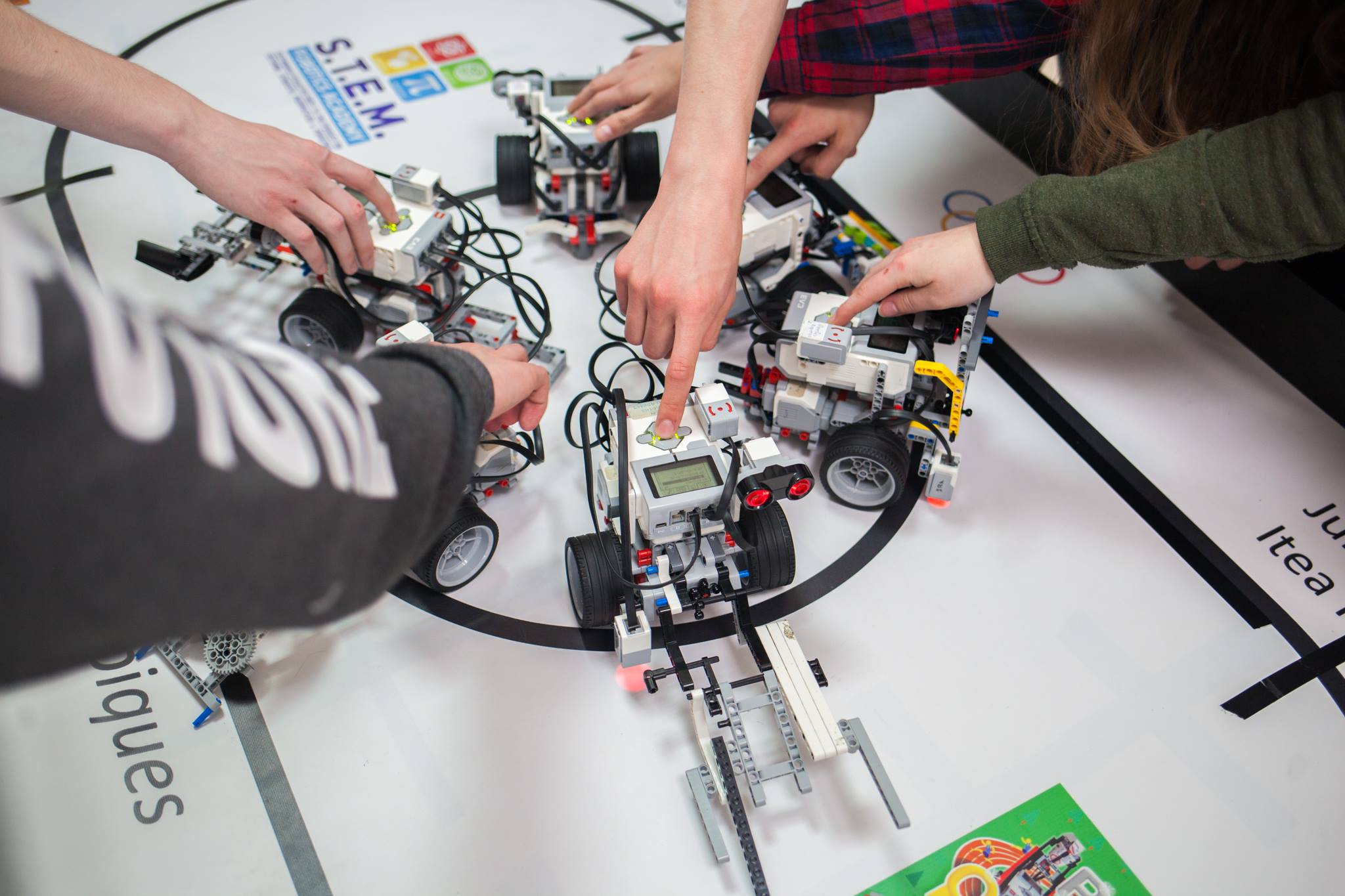 Fotografia przedstawia uczniów w pracowni informatycznej, którzy budują miniaturowe kołowe pojazdy mechaniczne.